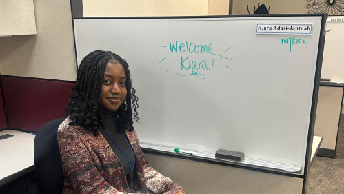 Student at office in front of welcome sign