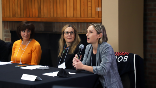 A young woman from the Rutgers Business School speaking into a microphone while two other panelists look on