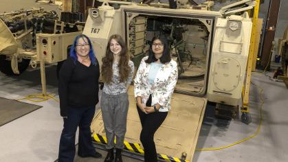 Students with site mentor in front of machine