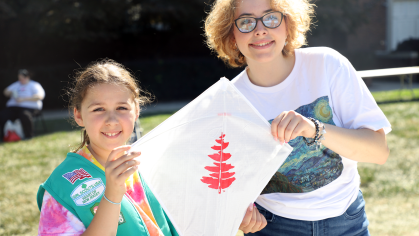 A Douglass Student helps a girl scout make a kite 