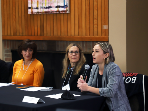 A young woman from the Rutgers Business School speaking into a microphone while two other panelists look on