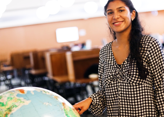 Student stands pointing at globe