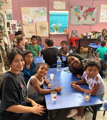 Students sit at table with children in classroom