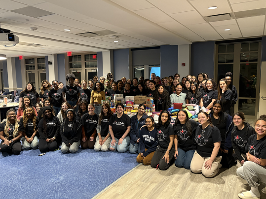 Large group of students around food and goods from a collection drive