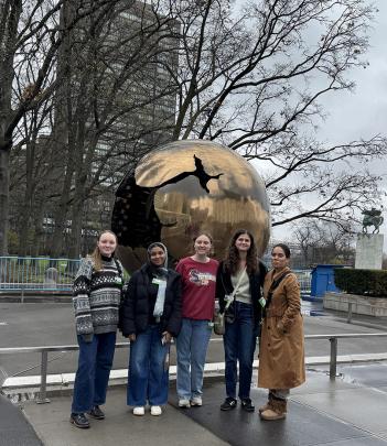 Students stand in front of sculpture
