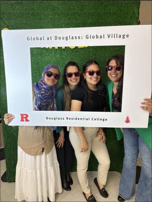 Students and faculty pose with sunglasses in banner