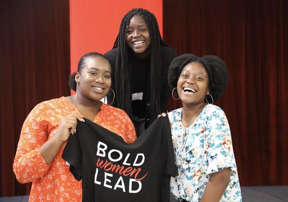 Three people holding Bold Women Lead t-shirt